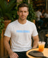 Man wearing a white t-shirt with 'Pickleball' text, sitting at an outdoor cafe.